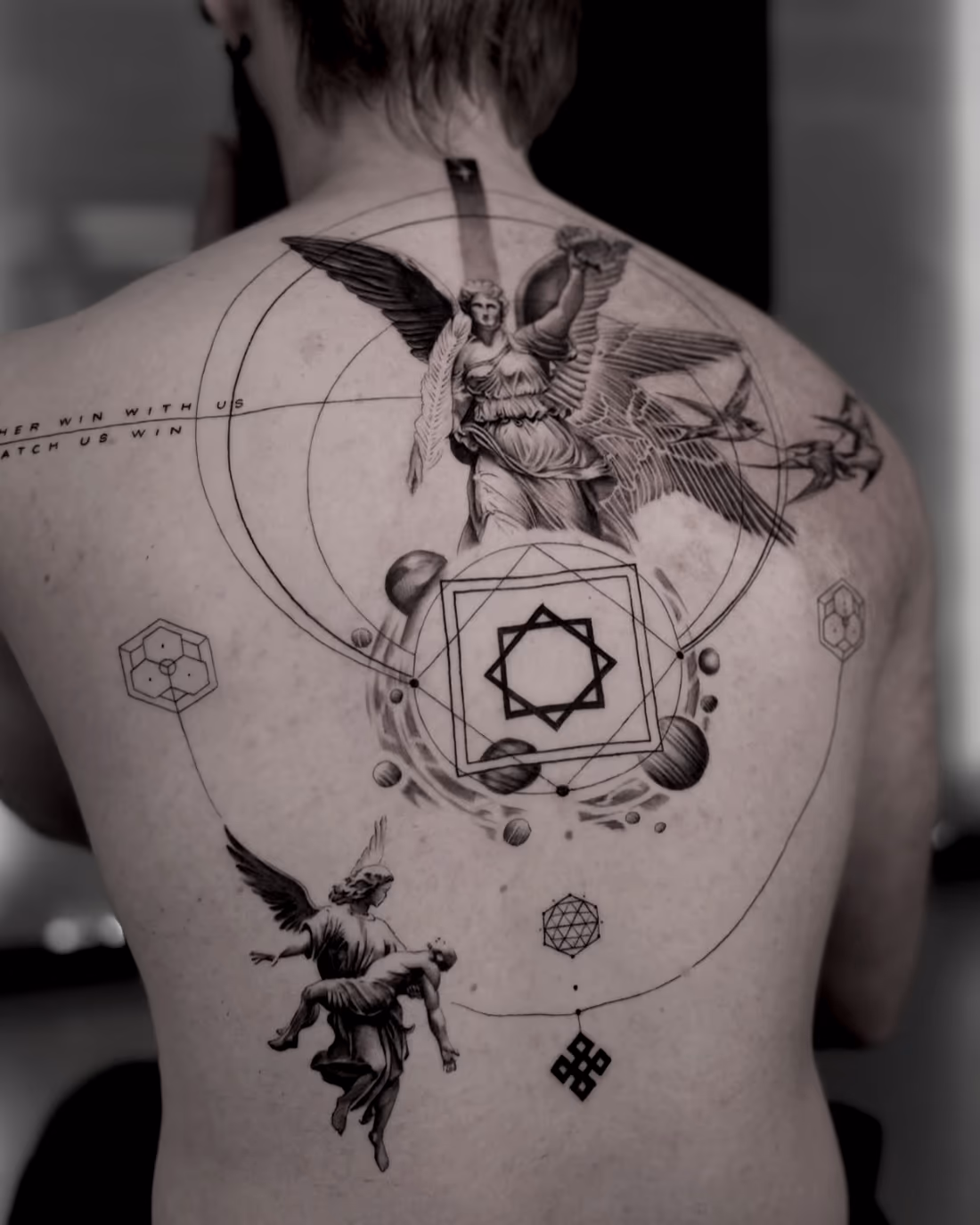 Wide circular structure across the whole back with winged classical figures and a central geometric core